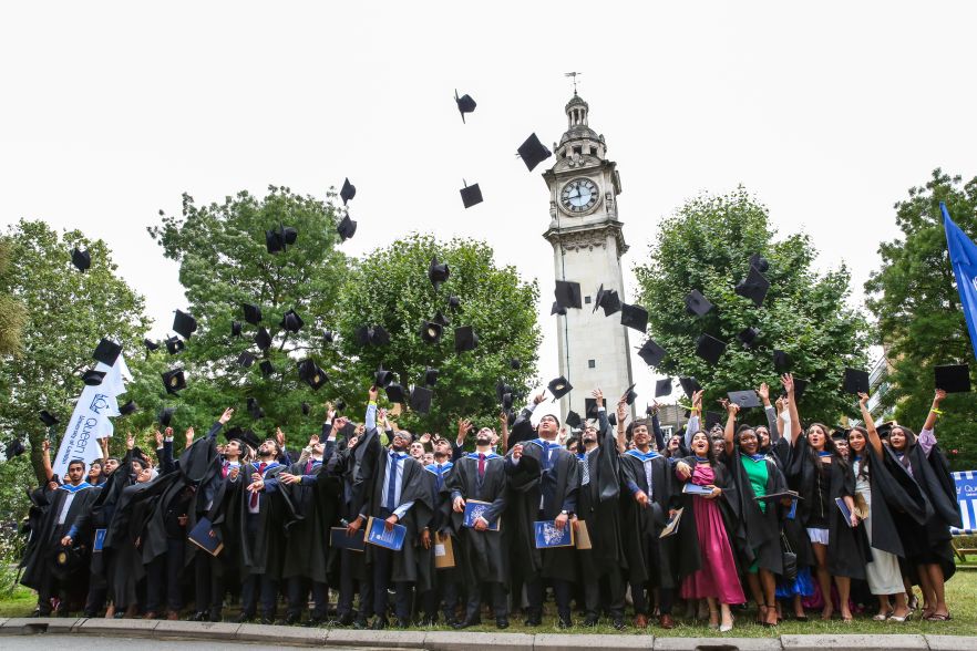 Graduates throw their hats in the air outside Queen Mary University